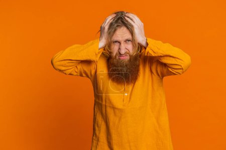 Sad young Caucasian man feeling hopelessness loneliness, nervous breakdown, loses becoming surprised by lottery results, bad fortune, loss unlucky news. Redhead guy isolated on orange background