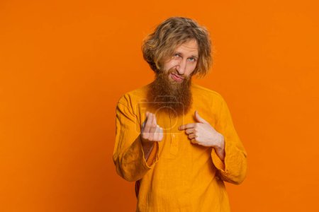 Give me money, please. Caucasian man rubbing fingers show cash gesture, demands to pay back the debt take loan do shopping begging investment reward. Redhead young guy isolated on orange background