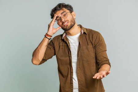 Sad young Indian man feeling hopelessness loneliness, nervous breakdown, loses becoming surprised by lottery results, bad fortune, loss unlucky news. Attractive Hindu guy isolated on gray background