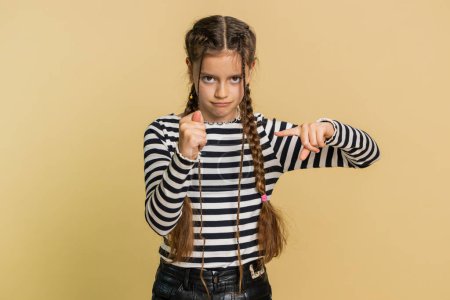 Angry preteen child girl kid showing fig negative gesture, you dont get it anyway. Rapacious, avaricious, acquisitive. Body language. Refusal fig sign. Teenager children isolated on beige background