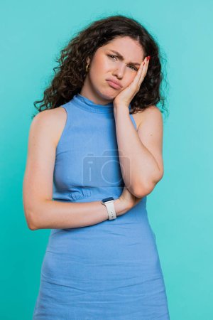 Sad woman feeling hopelessness loneliness, nervous breakdown, loses becoming surprised by lottery results, bad fortune, loss unlucky news. Young adult girl isolated on studio blue background. Vertical