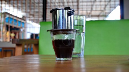 Hot coffee dripping in Vietnamese style. Hot coffee on a wooden table