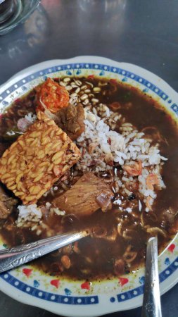Téléchargez les photos : Rawon. Soupe indonésienne de bœuf noir dans une assiette. servi avec chou, chili sambal et tempeh - en image libre de droit