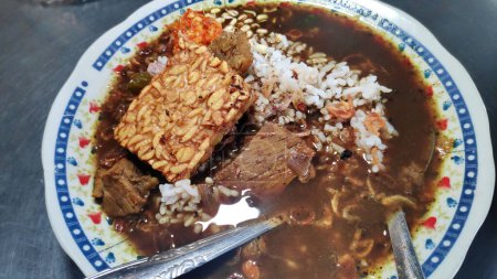 Téléchargez les photos : Rawon. Soupe indonésienne de bœuf noir dans une assiette. servi avec chou, chili sambal et tempeh - en image libre de droit