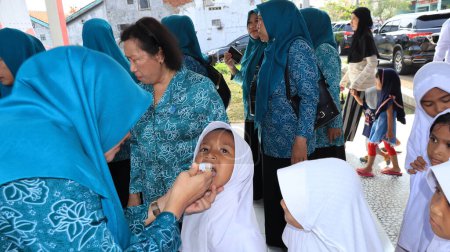 Téléchargez les photos : Des élèves du primaire reçoivent des gouttelettes de vaccin antipoliomyélitique pour prévenir une épidémie plus importante, Pekalongan Indonésie 16 janvier 2024 - en image libre de droit