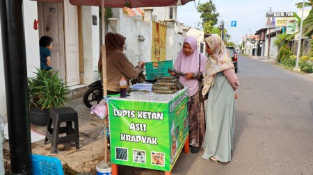 Téléchargez les photos : Vendeur de lopis Lupis est un gâteau sucré indonésien traditionnel à base de riz collant tout en servant les clients, Pekalongan Avril 15 2024 - en image libre de droit