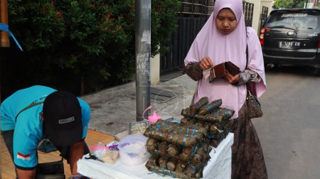 Téléchargez les photos : Vendeur de lopis Lupis est un gâteau sucré indonésien traditionnel à base de riz collant tout en servant les clients, Pekalongan Avril 15 2024 - en image libre de droit