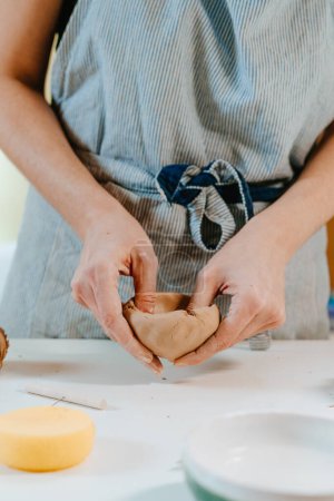 Téléchargez les photos : Gros plan d'une artisanale sculptant une tasse avec ses mains dans son atelier. Concentration sélective. - en image libre de droit