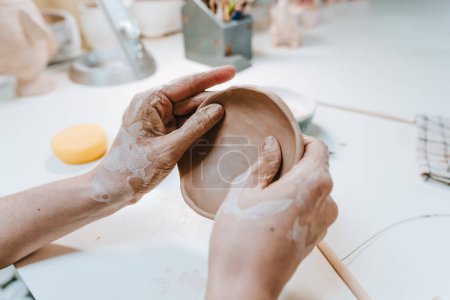Téléchargez les photos : Mains féminines travaillant avec de l'argile en atelier de poterie. Concentration sélective. - en image libre de droit