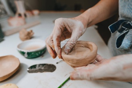 Photo for Close up of female hands working with clay making a cup in a workshop. Selective focus. - Royalty Free Image