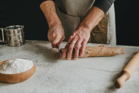Photo for Unrecognizable man cutting the dough with a knife on a white background. Close-up of male hands preparing homemade noodles. Selective focus. - Royalty Free Image