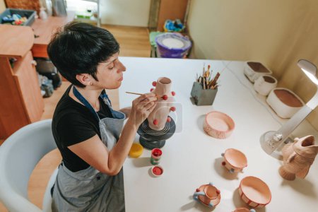 Photo for Young woman potter entrepreneur making a vase sitting in workshop. Small business concept. Selective focus. - Royalty Free Image