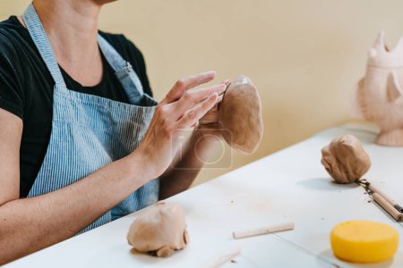 Foto de Joven alfarera esculpiendo una taza con las manos en su taller. Primer plano de las manos femeninas. Enfoque selectivo. - Imagen libre de derechos