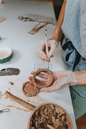 Téléchargez les photos : Gros plan de femmes travaillant avec de l'argile faisant une tasse dans un atelier. Concentration sélective. - en image libre de droit