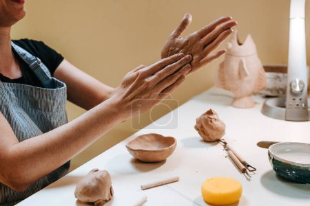 Photo for Young woman potter sculpting a cup with her hands in her workshop. Close-up of female hands. Selective focus. - Royalty Free Image