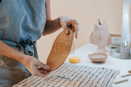 Photo for Young woman potter rolling clay in her workshop. Close up of female hands. Selective focus. - Royalty Free Image