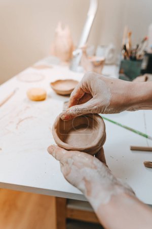 Téléchargez les photos : Gros plan de mains féminines faisant une tasse d'argile dans un atelier. Concentration sélective. - en image libre de droit
