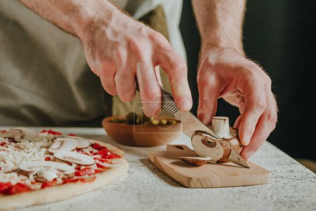 Photo for Close-up of chef preparing pizza cutting mushrooms. Selective focus. - Royalty Free Image