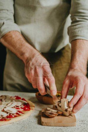 Photo for Close-up of chef preparing pizza cutting mushrooms. Selective focus. - Royalty Free Image