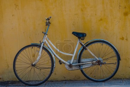 Old bicycle with yellow wall as background.