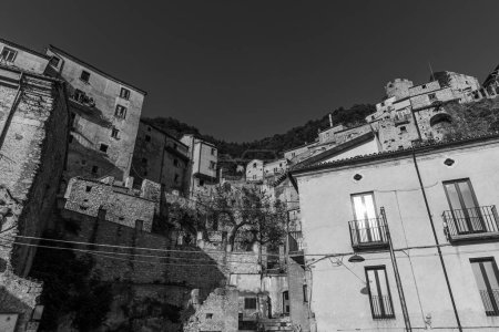 Foto de Pesche, pueblo en la provincia de Isernia, en Molise, encaramado a lo largo de las empinadas laderas del Monte San Marco, una mancha blanca contra el verde de la montaña y el gris de las piedras. - Imagen libre de derechos