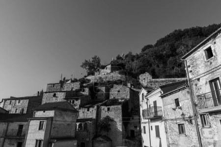 Foto de Pesche, pueblo en la provincia de Isernia, en Molise, encaramado a lo largo de las empinadas laderas del Monte San Marco, una mancha blanca contra el verde de la montaña y el gris de las piedras. - Imagen libre de derechos