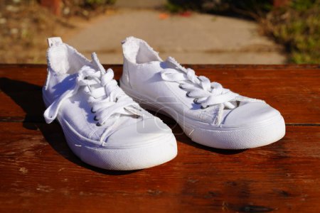 Téléchargez les photos : Chaussures basses blanches pour femmes sur un présentoir de table en bois. - en image libre de droit
