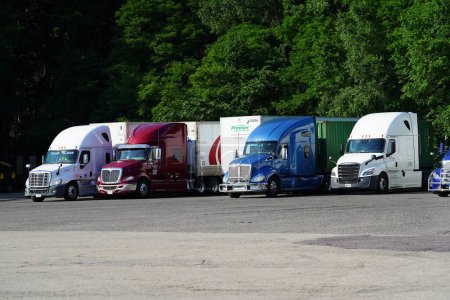 Photo for New Lisbon, Wisconsin USA - June 12rh, 2023: Different colored Semi trucks sit parked at a tuck rest stop. - Royalty Free Image