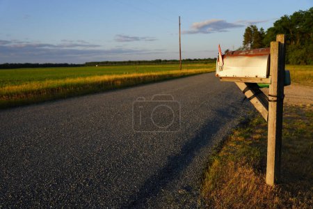 Foto de Buzón antiguo y oxidado frente a un camino rural - Imagen libre de derechos