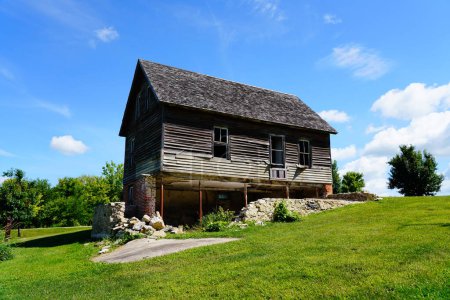 Foto de Antigua casa de madera vintage abandonada se sienta en la ladera de Ripon, Wisconsin durante el hermoso clima nublado de julio. - Imagen libre de derechos