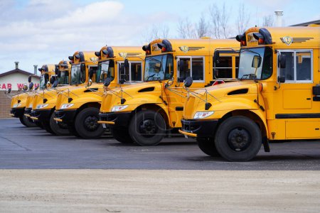 Foto de Elory, Wisconsin, EE.UU. - 15 de abril de 2022: Una línea de autobuses escolares amarillos estacionados y leídos para ser utilizados. - Imagen libre de derechos