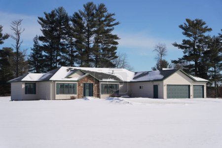 Foto de Nueva Lisboa, Wisconsin, EE.UU. - 10 de enero de 2022: Tan y Green garaje de dos vehículos rancho de una sola capa se sienta en el campo durante el invierno. - Imagen libre de derechos