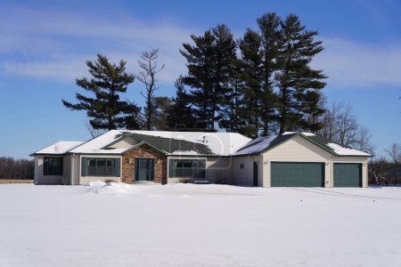 Photo for New Lisbon, Wisconsin USA - January 10th 2022: Tan and Green two vehicle garage single layer ranch house sits out on the countryside during the winter. - Royalty Free Image