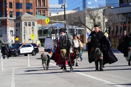 Photo for Milwaukee, Wisconsin USA - March 12th, 2022: Men and women dressed up in Irish Medieval costumes and carrying swords while walking in St. Patrick's Day parade - Royalty Free Image