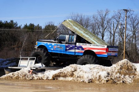 Téléchargez les photos : Montello, Wisconsin USA - 18 Mars, 2023 : Le propriétaire d'une entreprise utilise un vieux camion monstre Ford avec des graphiques drapeau américain pour annoncer leur entreprise. - en image libre de droit
