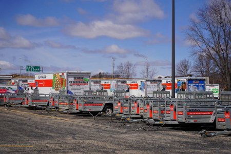 Foto de Baraboo, Wisconsin, EE.UU. - 19 de abril de 2022: Los remolques y camiones U-Haul estacionan y almacenan en un estacionamiento listo para ser utilizado. - Imagen libre de derechos