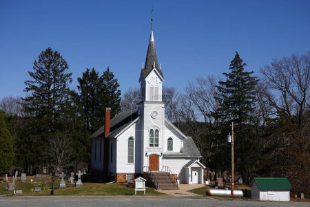 Foto de Nueva Lisboa, Wisconsin, EE.UU. - 22 de abril de 2022: La Iglesia Cristiana Blanca se sienta en la ladera del campo. - Imagen libre de derechos