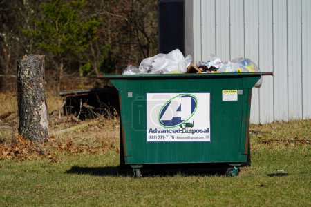 Téléchargez les photos : New Lisbon, Wisconsin États-Unis - avril 12th, 2023 : Metal Green benne à ordures de l'élimination avancée se trouve à l'extérieur plein de déchets. - en image libre de droit