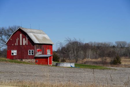 Photo for New Lisbon, Wisconsin USA - April 23rd, 2022: Abandoned red barn house sits on hillside out on the countryside - Royalty Free Image