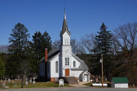 Foto de Nueva Lisboa, Wisconsin, EE.UU. - 22 de abril de 2022: La Iglesia Cristiana Blanca se sienta en la ladera del campo. - Imagen libre de derechos