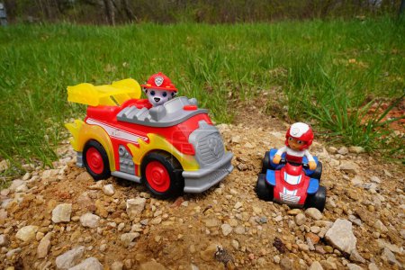 Photo for New Lisbon, Wisconsin USA May 11th, 2023: Paw Patrol Marshall Fire rescue pup action figure and Ryder action figure children toys sit outside during spring season. - Royalty Free Image