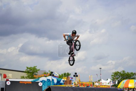 Photo for Fond du Lac, Wisconsin USA - July 14th, 2019: Bicycle stuntmen on BMX doing stunts on half-pipe ramps for a crowd of people at Fond du Lac county fair. - Royalty Free Image