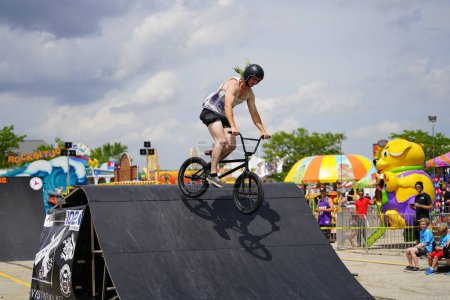 Photo for Fond du Lac, Wisconsin USA - July 14th, 2019: Bicycle stuntmen on BMX doing stunts on half-pipe ramps for a crowd of people at Fond du Lac county fair. - Royalty Free Image