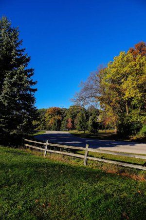 Photo for Wooden fence sits in front of autumn colored forest during the fall season in Fond du Lac, Wisconsin - Royalty Free Image