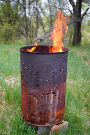 Foto de El barril de basura en llamas se sienta afuera durante el verano. - Imagen libre de derechos
