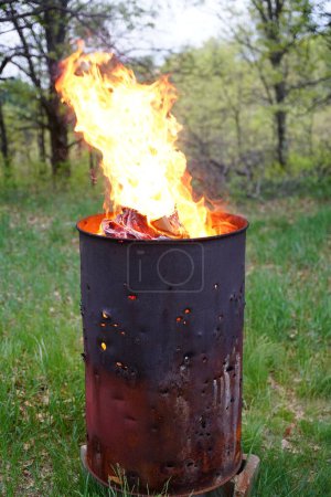 Photo for Burning trash barrel sits outside during the summer. - Royalty Free Image