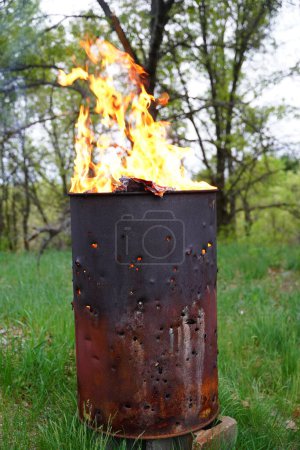 Téléchargez les photos : Brûler le tonneau de déchets se trouve à l'extérieur pendant l'été. - en image libre de droit