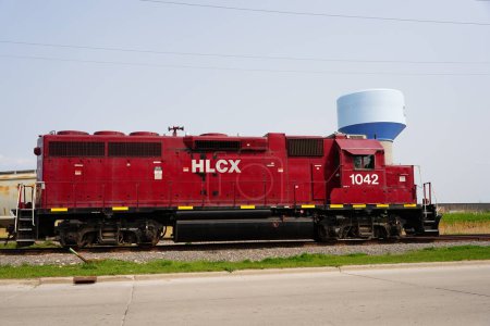 Photo for Green Bay, Wisconsin USA - May 18th, 2023: Red HLCX Helm Financial Locomotive train engine sits parked at a railway station. - Royalty Free Image