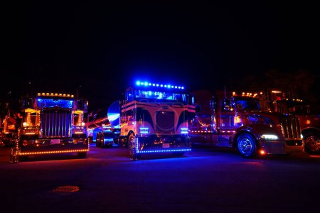 Foto de Waupun, Wisconsin, EE.UU. - 11 de agosto de 2023: Grandes camiones de plataforma y semirremolques brillaron durante la noche con sus luces amarillas de precaución encendidas. - Imagen libre de derechos