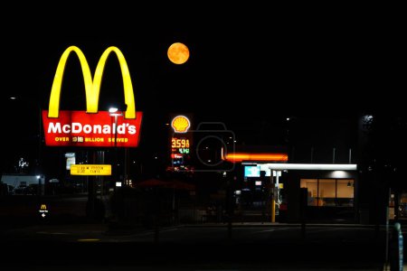 Foto de Ripon, Wisconsin dells USA - 4 de agosto de 2023: La súper luna naranja cuelga cerca del letrero del restaurante McDonald 's durante la noche. - Imagen libre de derechos